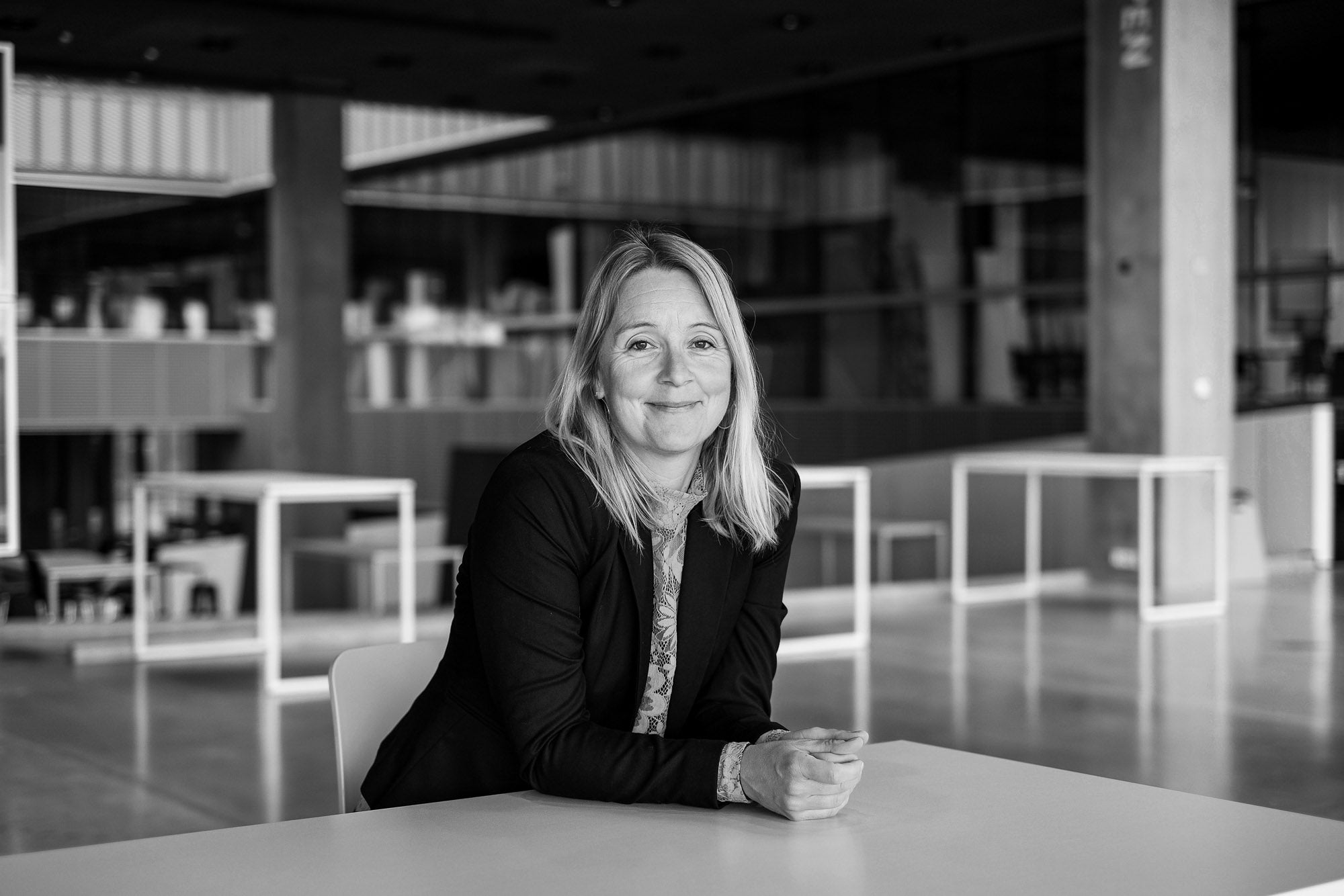 sort/hvid billede af kvinde stående ved bord i åbent kontorrum