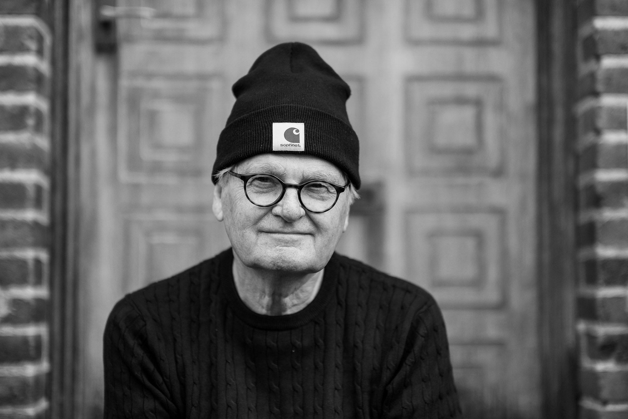 nærbillede af mand med briller og carhartt hue foran stor trædør